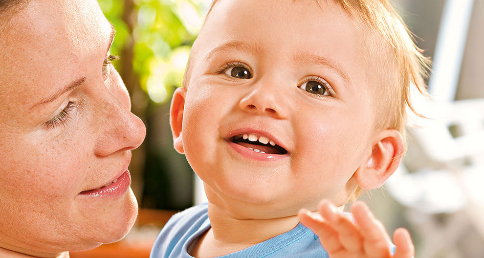 A woman and a baby are in close proximity, with the woman looking down at the baby.