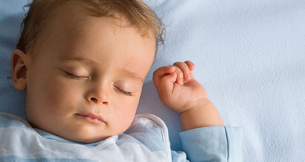 A baby is sleeping on a blue sheet.